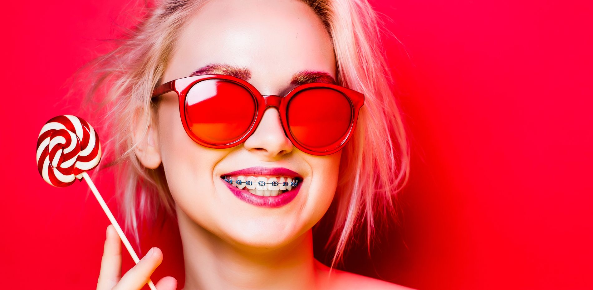 Woman smiling with her braces and a lolipop